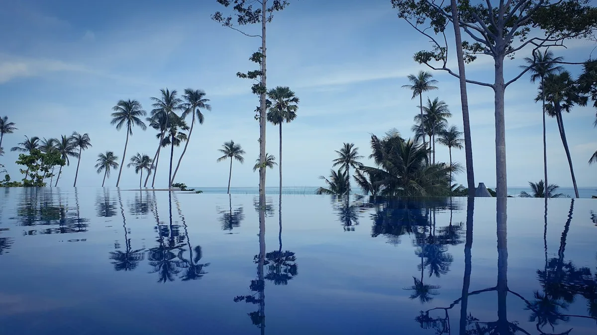 Пальмы отражаются в воде на территории Hyatt Regency Koh Samui.