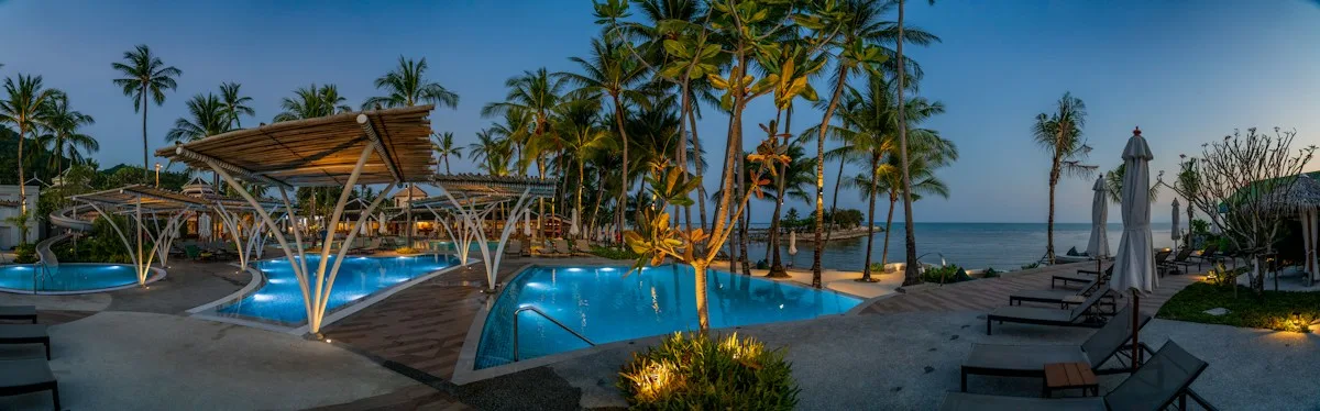 Бассейны и пальмы OUTRIGGER Koh Samui Beach Resort вечером.